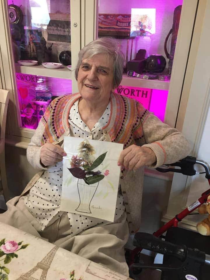 elderly lady holding up a piece of art she created
